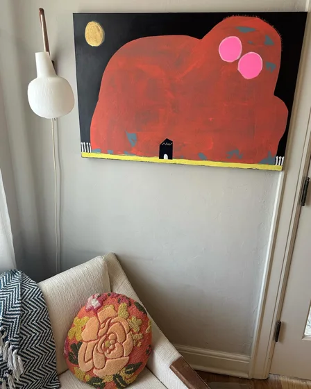 Daemon i. A large red rounded form with two pink circles and a tiny black doorway against a dark background.