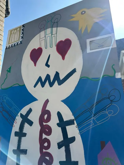 Inner Worlds. A large white figure with red heart-shaped eyes and a purple spiral torso, surrounded by symbols against a blue and gray background.